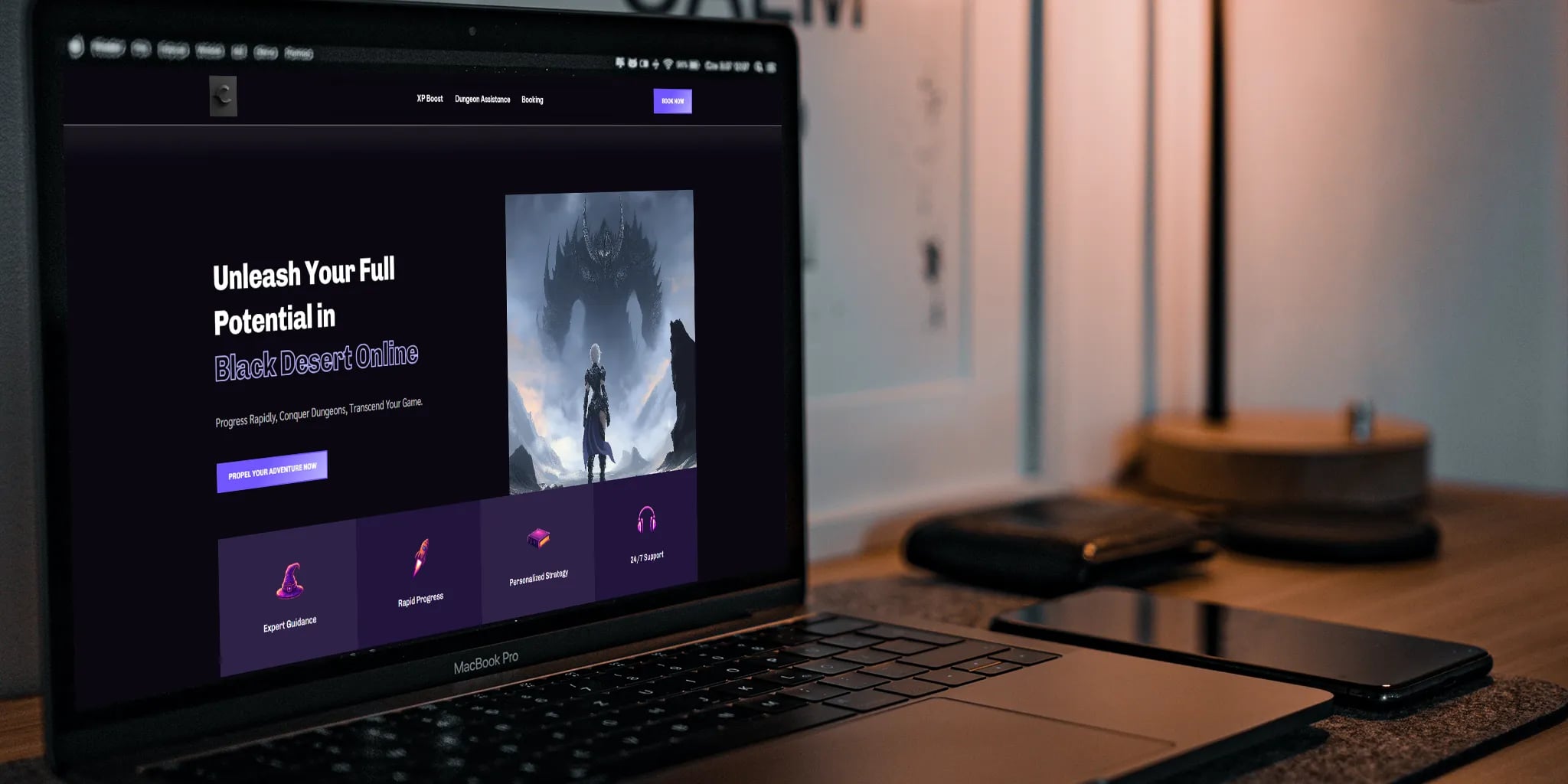 A laptop showcasing the Black Desert Online website with an inviting message, expert guidance, and 24/7 support. The setup includes two smartphones and a lamp, creating a cozy gaming workspace.